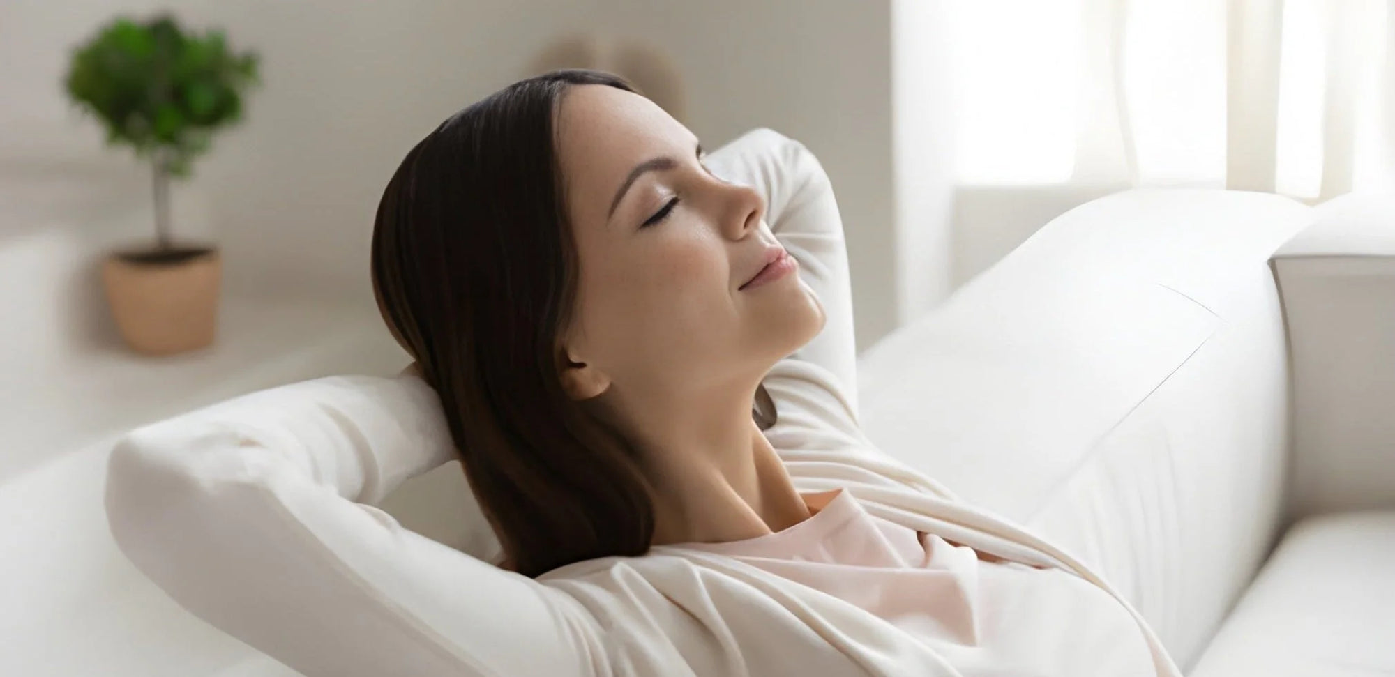 Woman relaxing due to CleanForge comforts on a white couch with eyes closed in a bright room